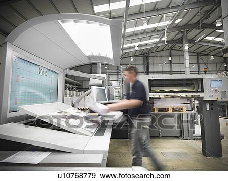 Stock Photo - Worker examining pages in press. Fotosearch