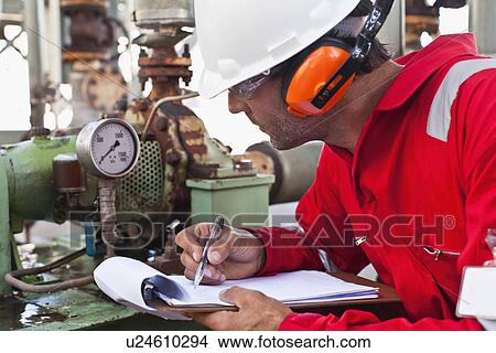 Worker noting gauge at oil refinery View Large Photo Image Picture - Worker noting gauge at oil refinery. Fotosearch