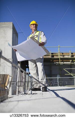 Worker reading blueprints on site View Large Photo Image Stock Image - Worker reading blueprints on site. Fotosearch