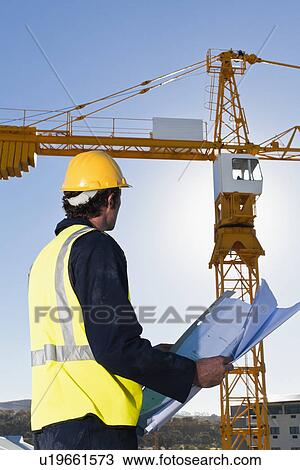 Worker reading blueprints on site View Large Photo Image Stock Image - Worker reading blueprints on site. Fotosearch
