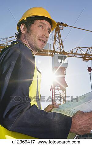 Worker reading blueprints on site View Large Photo Image Stock Photo - Worker reading blueprints on site. Fotosearch