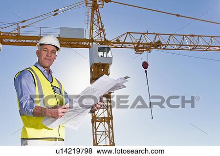 Worker reading blueprints on site View Large Photo Image Stock Photo - Worker reading blueprints on site. Fotosearch
