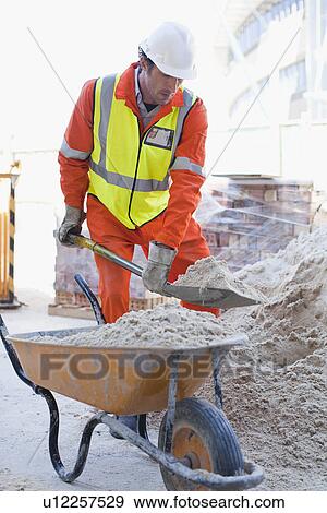 Worker shoveling concrete on site View Large Photo Image Stock Photo - Worker shoveling concrete on site. Fotosearch