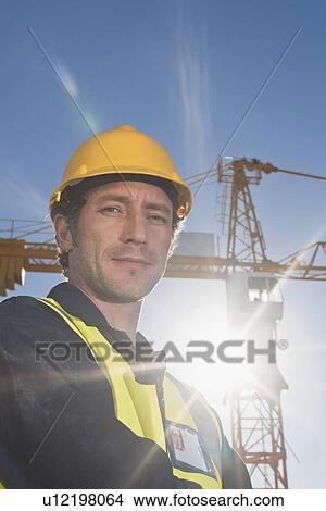 Worker standing at construction site View Large Photo Image Picture - Worker standing at construction site. Fotosearch