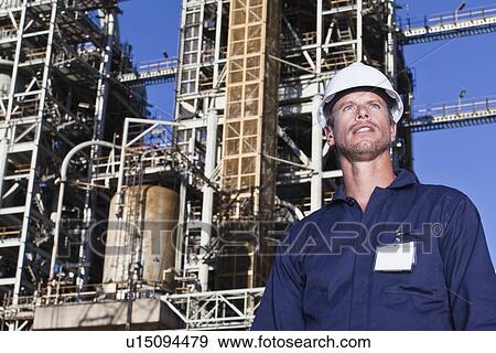 Stock Photo - Worker standing at oil refinery. Fotosearch