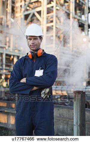 Worker standing at oil refinery View Large Photo Image Stock Photograph - Worker standing at oil refinery. Fotosearch