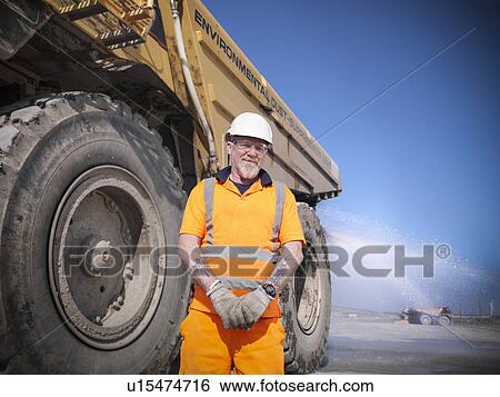 Worker standing by truck at coal mine View Large Photo Image Stock Photograph - Worker standing by truck at coal mine. Fotosearch