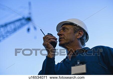 Worker using walkie talkie on site View Large Photo Image Stock Image - Worker using walkie talkie on site. Fotosearch