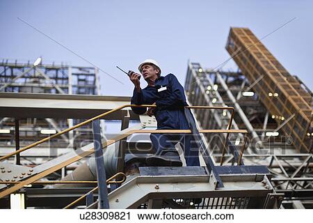 Worker using walkie talkie on site View Large Photo Image Stock Image - Worker using walkie talkie on site. Fotosearch