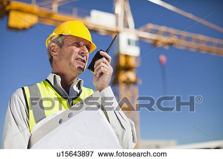 Stock Photo - Worker using walkie talkie on site. Fotosearch