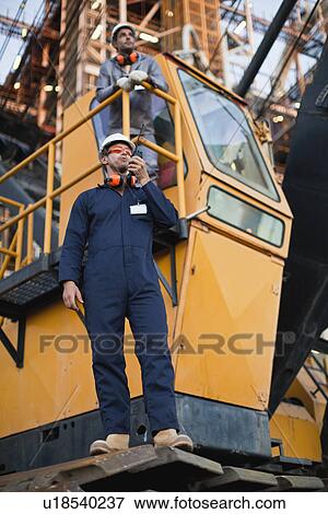 Worker using walkie talkie on site View Large Photo Image Stock Photo - Worker using walkie talkie on site. Fotosearch