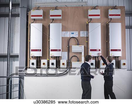 Stock Photography - Workers checking solar panel controls. Fotosearch
