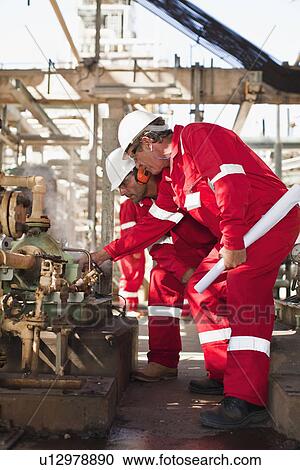 Stock Image - Workers examining equipment on site. Fotosearch