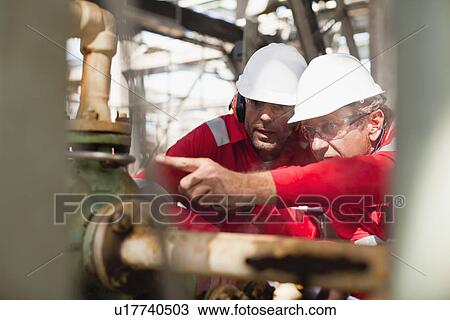 Workers examining equipment on site View Large Photo Image Stock Image - Workers examining equipment on site. Fotosearch