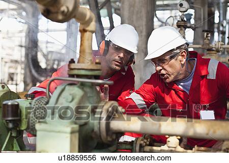 Workers examining equipment on site View Large Photo Image Stock Photograph - Workers examining equipment on site. Fotosearch