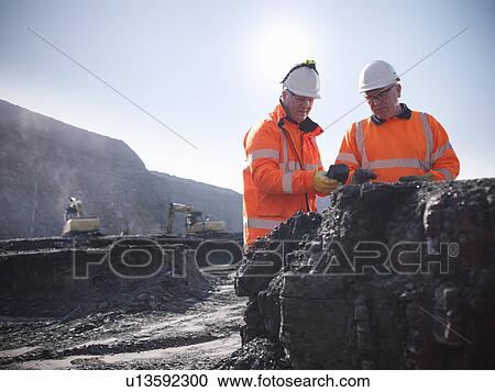 Stock Image - Workers inspecting coal at mine. Fotosearch