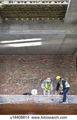 Picture - Workers laying brick on site. Fotosearch