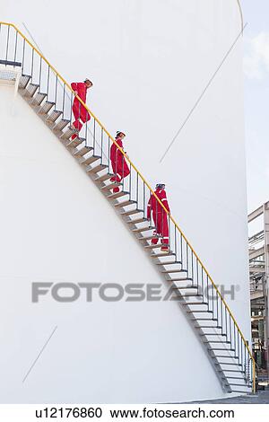 Stock Image - Workers on steps at chemical plant. Fotosearch