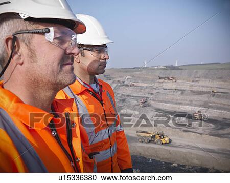 Stock Image - Workers overlooking coal mine. Fotosearch
