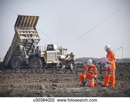Stock Image - Workers reading blueprints at coal mine. Fotosearch