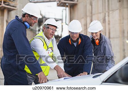 Workers reading blueprints at plant View Large Photo Image Stock Image - Workers reading blueprints at plant. Fotosearch