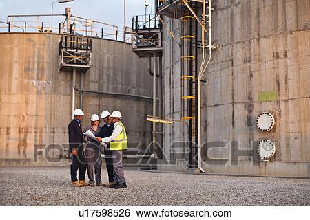 Stock Photograph - Workers reading blueprints at plant. Fotosearch