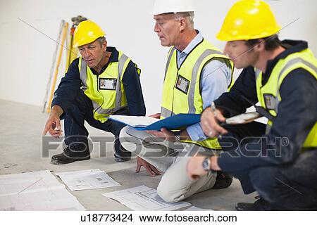 Workers reading blueprints on site View Large Photo Image Picture - Workers reading blueprints on site. Fotosearch