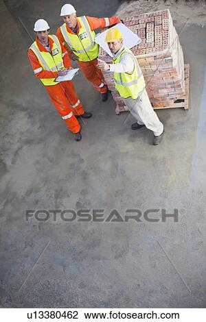 Workers reading blueprints on site View Large Photo Image Stock Image - Workers reading blueprints on site. Fotosearch