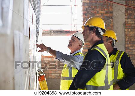 Workers reading blueprints on site View Large Photo Image Stock Photo - Workers reading blueprints on site. Fotosearch