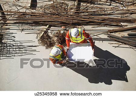 Stock Photo - Workers reading blueprints on site. Fotosearch