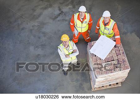 Stock Photograph - Workers reading blueprints on site. Fotosearch