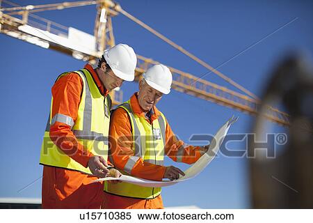 Workers reading blueprints on site View Large Photo Image Stock Photography - Workers reading blueprints on site. Fotosearch