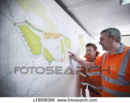 Stock Photo - Workers reading map in office. Fotosearch