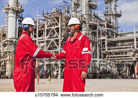 Picture - Workers shaking hands at oil refinery. Fotosearch