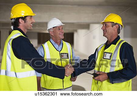 Stock Image - Workers shaking hands on site. Fotosearch