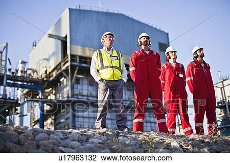Stock Image - Workers standing at chemical plant. Fotosearch