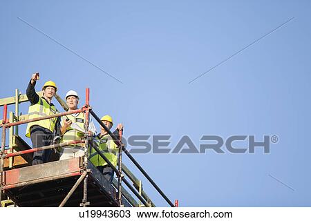 Workers standing on scaffolding on site View Large Photo Image Stock Image - Workers standing on scaffolding on site. Fotosearch
