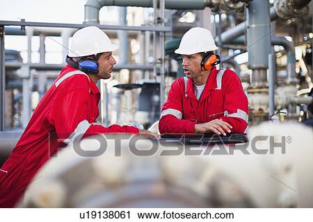 Stock Image - Workers talking at chemical plant. Fotosearch