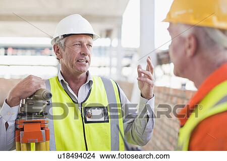 Picture - Workers talking at construction site. Fotosearch