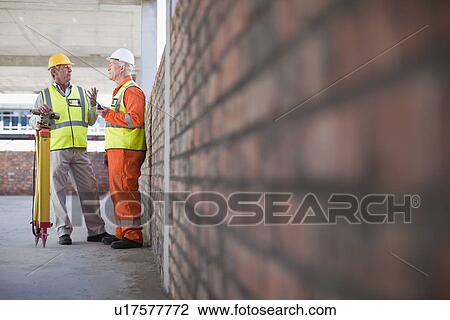 Workers talking at construction site View Large Photo Image Stock Image - Workers talking at construction site. Fotosearch