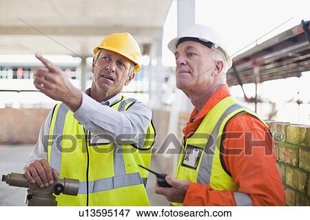 Stock Photo - Workers talking at construction site. Fotosearch