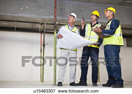 Stock Photo - Workers talking at construction site. Fotosearch