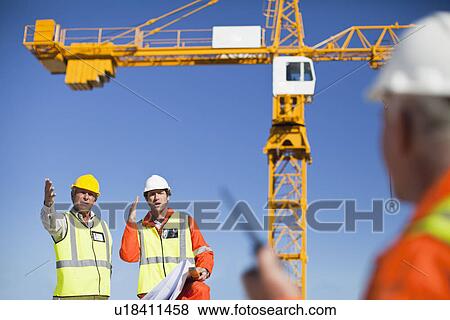 Stock Photo - Workers talking at construction site. Fotosearch