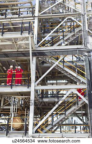 Picture - Workers talking at oil refinery. Fotosearch