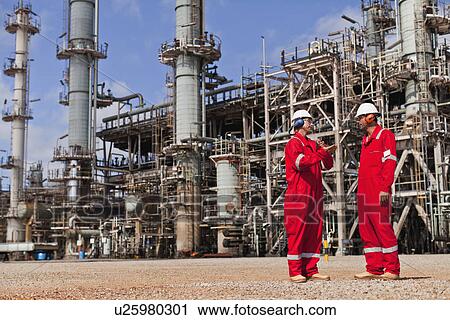 Stock Image - Workers talking at oil refinery. Fotosearch