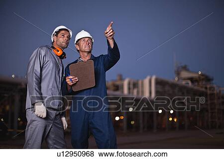 Stock Photo - Workers talking at oil refinery. Fotosearch