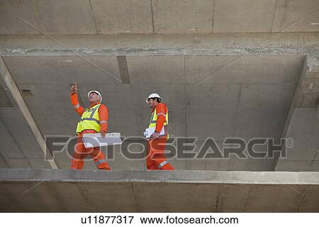 Stock Photo - Workers walking at construction site. Fotosearch