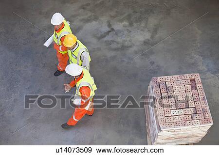 Workers walking at construction site View Large Photo Image Stock Photo - Workers walking at construction site. Fotosearch