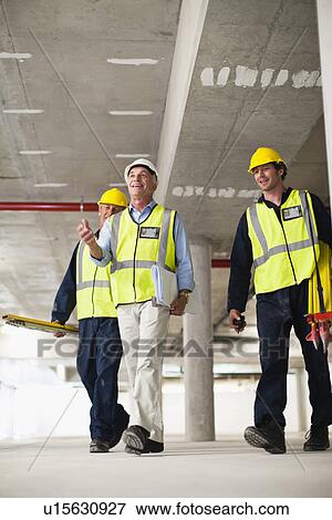 Stock Photo - Workers walking at construction site. Fotosearch