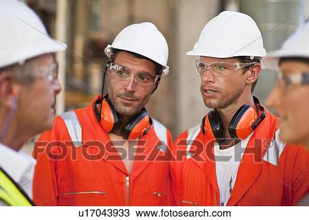 Stock Image - Workers walking at oil refinery. Fotosearch